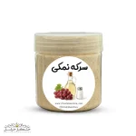 عکس نمای نزدیک از شیشه پر شده با چاشنی سرکه نمکی خانگی، حاوی تکه‌های سیر، فلفل قرمز و سبزیجات معطر، با برچسب طلایی رنگ "چاشنی سرکه نمکی".
