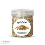 نمای نزدیک و باکیفیت از دانه‌های کروی و طلایی‌رنگ تخم گشنیز پاک‌سازی شده در بسته‌بندی اختصاصی خشکبار استور